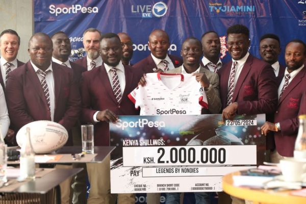 Kenya rugby legends pose with the cheque alongside SportPesa's PR manager Willis Ojwang'. PHOTO| SportPesa